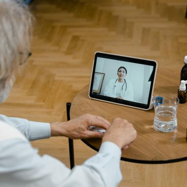 An elderly man participates in a telemedicine session using a tablet.